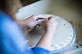Close up female artist at pottery wheel