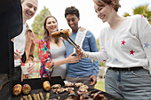 Happy friends barbecuing corn at barbecue grill