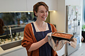 Happy woman baking loaf cake in kitchen