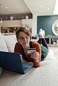 Young woman with credit card paying bills online at laptop