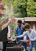 Happy friends barbecuing at barbecue grill on patio