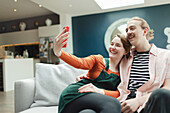 Happy couple taking selfie on living room sofa