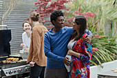Happy pregnant couple enjoying barbecue with friends