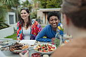 Happy couple enjoying lunch with friend at patio table