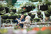 Couple shopping for hanging baskets in garden shop