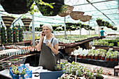 Female garden shop owner talking on smart phone