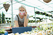 Female garden shop owner in face mask talking on phone