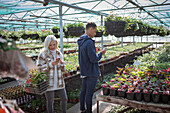 Couple with smart phones shopping in sunny garden shop