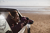 Woman with digital camera in convertible on beach