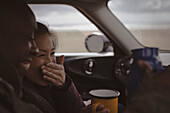 Happy couple drinking coffee in car