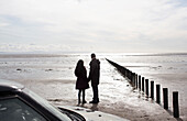 Silhouette of couple on wet sunny winter beach