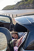 Affectionate couple laying in back of car on beach