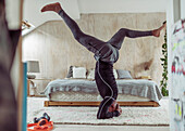 Man practicing headstand on bedroom rug