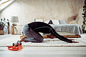 Man exercising in yoga childs pose on bedroom floor