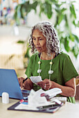 Woman with receipts budgeting at laptop