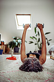 Woman exercising with dumbbells on rug