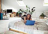 Woman with credit card paying bills at laptop on bed
