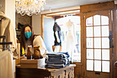 Female shop owner in face mask arranging display in boutique