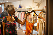 Female shop owner giving dress to customer in boutique