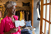 Smiling female shop owner holding open sign in boutique