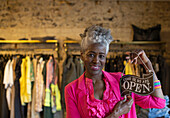 Senior female shop owner holding open sign