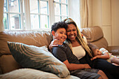 Happy mother and son hugging on living room sofa