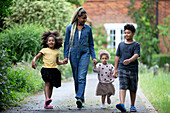 Mother and kids holding hands and walking on driveway