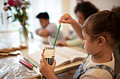 Girl with coloured pencils colouring at table