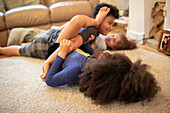Playful brother and sisters on living room floor