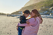 Mother holding son with Down Syndrome on sunny beach