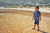 Happy boy with Down Syndrome wading in ocean surf on beach