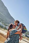 Happy, affectionate mother kissing son on beach