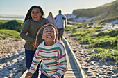 Carefree sisters running on sunny beach boardwalk