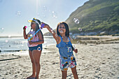 Sisters playing with bubbles on sunny beach