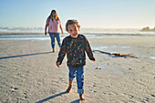 Cute boy with Down Syndrome walking on sunny beach