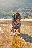 Mother and son playing, splashing in sunny ocean surf