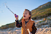 Boy with Down Syndrome blowing bubbles on beach