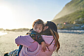 Mother holding son with Down Syndrome on beach