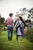 Couple holding hands and walking on allotment