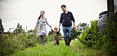 Family holding hands and walking in garden grass