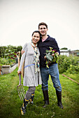 Happy couple with harvested vegetables in garden