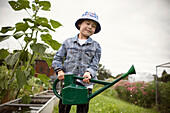 Smiling boy with watering can in garden