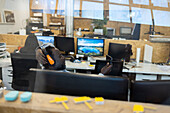 Businessman in headset using smart phone in open plan office