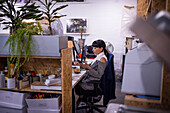 Businesswoman using smart phone at desk in creative office