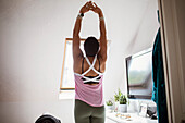 Woman exercising with arms raised at home