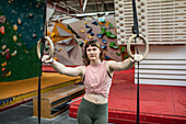 Determined young woman at gymnastics rings in climbing center
