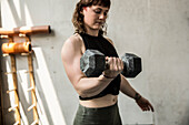 Strong young woman weight training with dumbbell