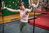 Young woman at gymnastics rings in climbing center