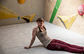 Smiling young female rock climber resting at rock wall