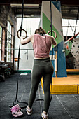 Young woman at gymnastics rings in climbing center